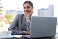 Portrait of successful business woman using laptop and smiling while sitting in cafe, outdoor Royalty Free Stock Photo