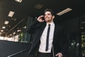 Portrait of successful businessman dressed in formal suit walking outside glass building, and talking on mobile phone Royalty Free Stock Photo