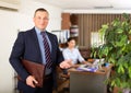 Portrait of successful businessman inviting to modern office