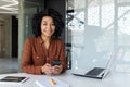 Portrait of successful businesswoman at workplace, female boss smiling and looking at camera, mature and satisfied latin Royalty Free Stock Photo