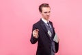 Portrait of successful conceited rich businessman offering money at camera. studio shot isolated, pink background