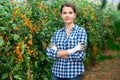 Successful female grower in greenhouse near yellow grape tomatoes