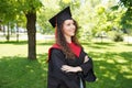 Portrait of successful graduate female student wearing cap outdoors near university