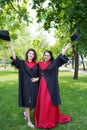 Portrait of successful graduate female students holding cap outdoors near university