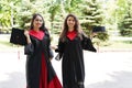 Portrait of successful graduate female students holding cap outdoors near university