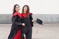 Portrait of successful graduate female students wearing cap outdoors near university