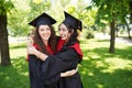 Portrait of successful graduate female students wearing cap outdoors near university