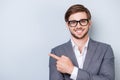 Portrait of successful handsome young man in formal wear with beaming smile, bristle and glasses pointing to the side Royalty Free Stock Photo