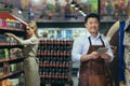 Portrait of a successful and happy Asian seller in a supermarket, a man in an apron