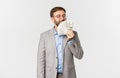 Portrait of successful happy businessman, wearing grey suit and glasses, smelling money and smiling delighted, standing