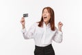 Portrait of successful happy and relieved asian woman screaming joyfully yes, raising hands up and cheering as holding Royalty Free Stock Photo
