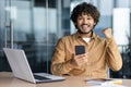 Portrait of successful hispanic young businessman, man smiling and looking at camera at workplace holding phone Royalty Free Stock Photo