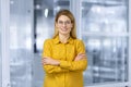 Portrait of successful mature business woman inside office, female worker in yellow shirt smiling and looking at camera Royalty Free Stock Photo