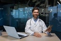 Portrait of successful mature doctor in medical coat with stethoscope beard and glasses, man holding tablet computer Royalty Free Stock Photo