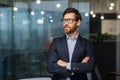 Portrait of successful mature investor, senior businessman inside office looking towards window smiling with crossed