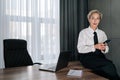 Portrait of successful middle-aged business woman using typing smartphone searching info sitting on office desk, looking Royalty Free Stock Photo