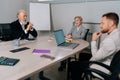 Portrait of successful middle-aged businesswoman attending meeting with diverse-ages colleagues in office. Experienced Royalty Free Stock Photo