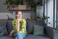 Portrait of successful middle-aged woman, housewife sitting on sofa in kitchen and smiling looking at camera Royalty Free Stock Photo