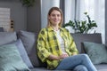 Portrait of successful middle-aged woman, housewife sitting on sofa in kitchen and smiling looking at camera Royalty Free Stock Photo