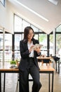 Successful Asian businesswoman leaning on the table, using her digital tablet