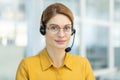 Portrait of successful smiling business woman with headset phone, mature experienced worker smiling and looking at Royalty Free Stock Photo