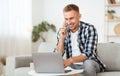 Portrait of successful smiling man using pc talking on cellphone Royalty Free Stock Photo