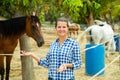 Successful woman farmer near enclosure with horses