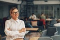 Portrait of successful woman manager standing with crossing hands in office on colleagues background Royalty Free Stock Photo