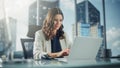 Portrait of Successful Young Businesswoman Sitting at Her Desk Working on Laptop Computer in Big Royalty Free Stock Photo