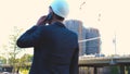 Portrait of a successful young handsome engineer, architect, builder, businessman, wearing a white helmet, in a suit, holding a pr