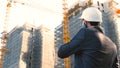 Portrait of a successful young handsome engineer, architect, builder, businessman, wearing a white helmet, in a suit, holding a pr