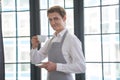 Portrait of a successful young man working as a professional barista, smiling at the camera and raising a cup with a Royalty Free Stock Photo