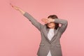 Portrait of successful young woman in business suit showing dab dance pose, famous internet meme of triumph Royalty Free Stock Photo