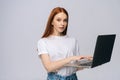 Portrait of successful young woman student holding laptop computer and typing on isolated background Royalty Free Stock Photo