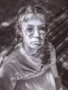A portrait of a sullen lady with two braids sitting on a bench in the shade. Black and white photo