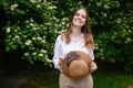 Portrait on a summer day near a jasmine bush of a happy female tourist with a straw hat in her hands, while on vacation