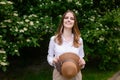 Portrait on a summer day near a jasmine bush of a happy female tourist with a straw hat in her hands, while on vacation