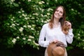 Portrait on a summer day near a jasmine bush of a happy woman with a straw hat in her hands.