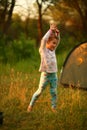 Portrait of a sunlit cheerful dancing girl while camping in the forest