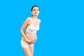 Portrait of supporting bandage against backache on pregnant woman in underwear at blue background with copy space. Mother is Royalty Free Stock Photo