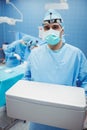 Portrait of surgeon holding ice box while colleagues performing operation Royalty Free Stock Photo