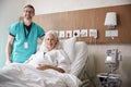 Portrait Of Surgeon Visiting Mature Female Patient In Hospital Bed