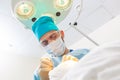 Portrait of a surgeon at work. Lamp in the background. The surgeon gives injections to the head. Hair transplant.