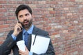 Portrait of a surprised amazed man in eyeglasses talking on mobile phone isolated on brick wall outdoors urban background Royalty Free Stock Photo