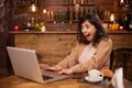 Portrait of surprised beautiful young woman sitting in front of her laptop in a coffee shop Royalty Free Stock Photo