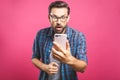 Portrait of a surprised casual man looking at mobile phone isolated over pink background Royalty Free Stock Photo