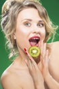 Portrait of Surprised Caucasian Blond Model Posing With Slice of Green Juicy Kiwi Fruit Royalty Free Stock Photo