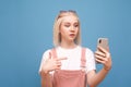 Portrait of a surprised cute girl shows finger on the smartphone in her hand and looks at the screen.Emotional teen girl in cute Royalty Free Stock Photo