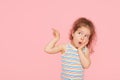 Portrait of surprised cute little toddler girl child over pink background. Looking at camera. Royalty Free Stock Photo