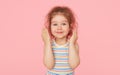 Portrait of surprised cute little toddler girl child over pink background. Looking at camera. Royalty Free Stock Photo